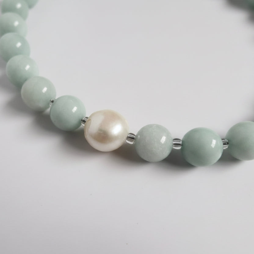 Necklace with green beads and a pearl on a white background